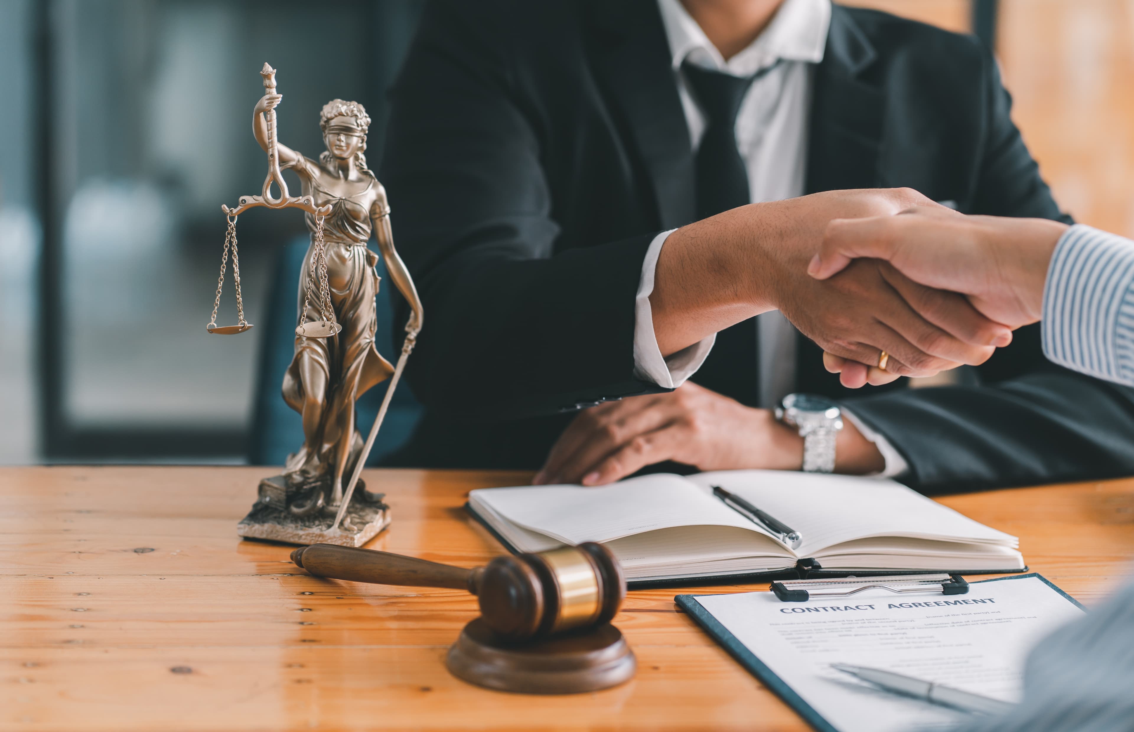 Lady Justice statue beside a contract handshake — Cronuss Associates